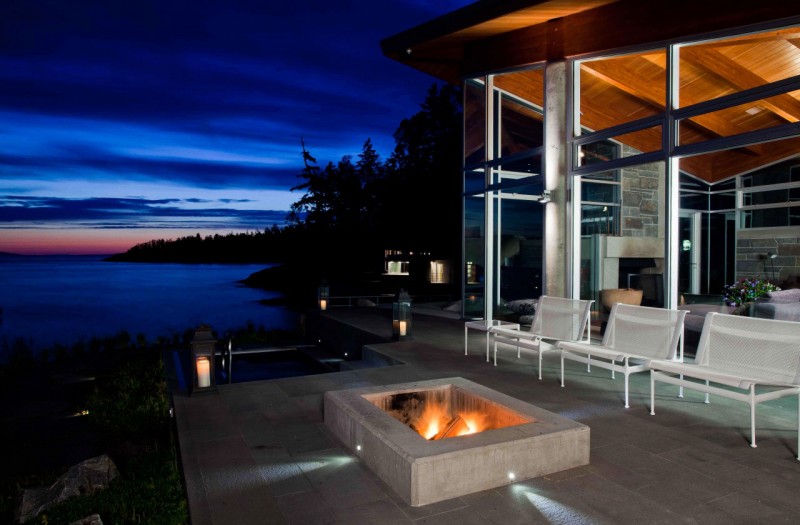 Sunset And Warm Mesmerizing Sunset And Beach View Warm Outdoor Fireplace Tough Metallic Chairs Glass Wall Sloping Roof Shiny Outdoor Lights Architecture Stunning Waterfront House With Lush Forest Landscape