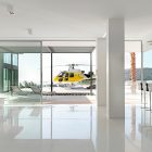Helicopter Landing With Lavish Helicopter Landing Area Design With Transparent Sliding Door Made From Glass Panels And Several White Sleeper Chairs Hotels & Resorts Fabulous Modern Villa In Spain With White Living Room Appearance